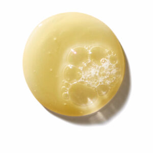 A round droplet of yellowish Invati Advanced Exfoliating shampoo - rich, featuring clusters of bubbles within it, set against a white background. - SAAB Salon Spa | Ottawa On, Canada