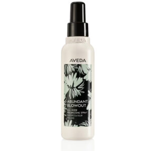 A white bottle of Abundant Blowout All-Over Volumizing Spray features a black and white floral label and a black spray nozzle. - SAAB Salon Spa | Ottawa On, Canada