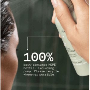A hand sprays Pure Abundance Style Pre from a green bottle labeled 