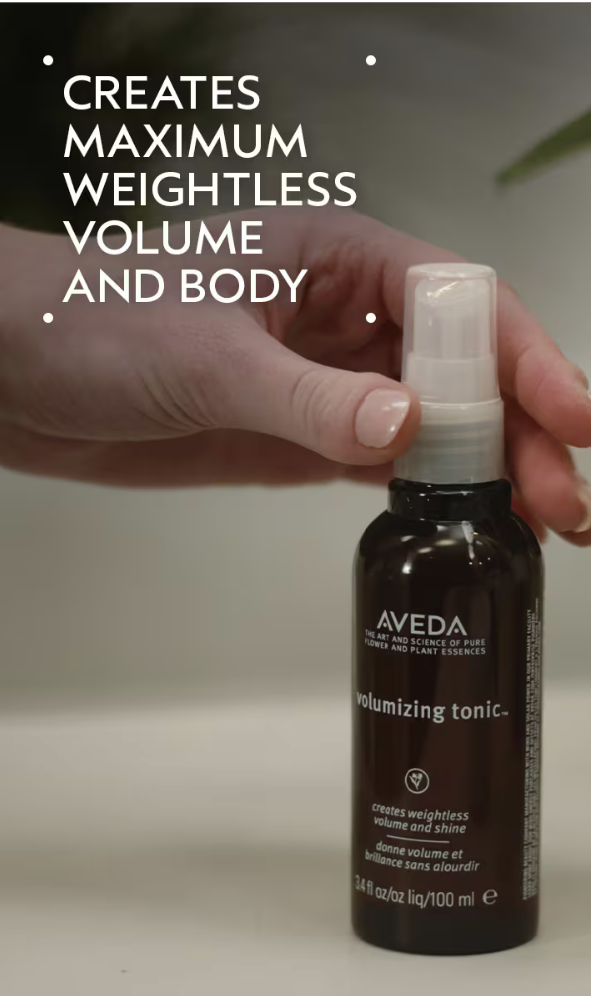 A hand holds a bottle of Volumizing Tonic, with text highlighting its ability to create maximum, weightless volume and body. - SAAB Salon Spa | Ottawa On, Canada