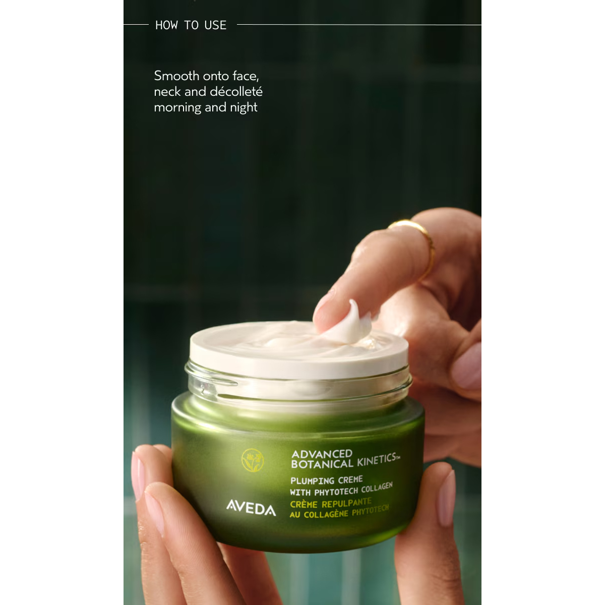 A hand holds an open jar of Advanced Botanical Kinetics Plumping Milky Lotion, with a finger scooping out the lotion. Instructions above recommend applying it morning and night. - SAAB Salon Spa | Ottawa On, Canada