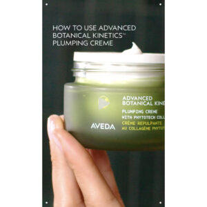 A hand holds an open jar of Advanced Botanical Kinetics Plumping Milky Lotion, with some lotion visible on the rim. - SAAB Salon Spa | Ottawa On, Canada