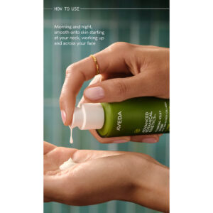A person dispenses Advanced Botanical Kinetics Plumping Milky Lotion, a white lotion, from a green Aveda bottle onto their palm against teal tiles, with usage instructions visible in the image. - SAAB Salon Spa | Ottawa On, Canada