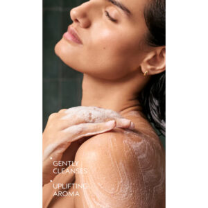 A person with eyes closed applies Beautifying Body Wash lather to their shoulder, with the text “Gently cleanses, uplifting aroma” overlaid on the left. - SAAB Salon Spa | Ottawa On, Canada