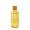 Clear glass bottle of Beautifying Composition Oil with a light yellow body and an orange screw cap. - SAAB Salon Spa | Ottawa On, Canada