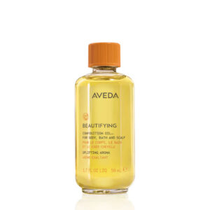 Clear glass bottle of Beautifying Composition Oil with a light yellow body and an orange screw cap. - SAAB Salon Spa | Ottawa On, Canada