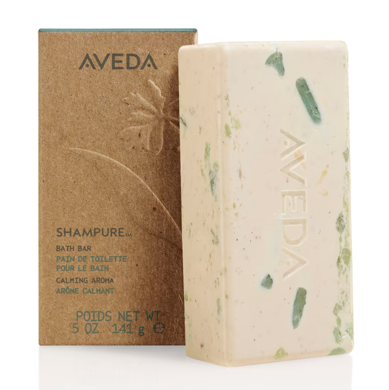 Rectangular beige Shampure Bath Bar with green flecks and a brand name embossed on the side, standing next to its brown cardboard packaging. - SAAB Salon Spa | Ottawa On, Canada